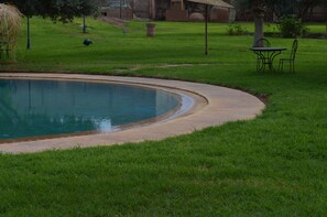 Una piscina al aire libre, sombrillas, sillones reclinables de piscina