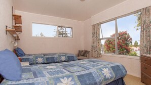 A bedroom with two beds, a window, and a dresser. - Holiday Haven - Whitianga Bach (Whitianga)