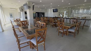 A spacious restaurant with wooden tables and chairs, a central bar area, and a modern interior design.