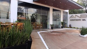 Un bâtiment moderne doté d’une entrée abritée, d’un espace extérieur aménagé pour s’asseoir et de plantes en pot.
