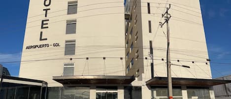 Un moderno edificio de hotel con un letrero llamativo que dice 'HOTEL' y 'AEROPUERTO - GDL'.