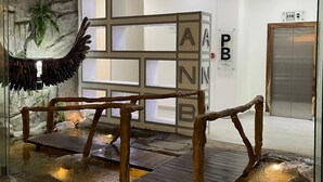 Un espace d’accueil agrémenté d’un mur en pierre, d’un banc en bois et d’un élément décoratif aquatique.