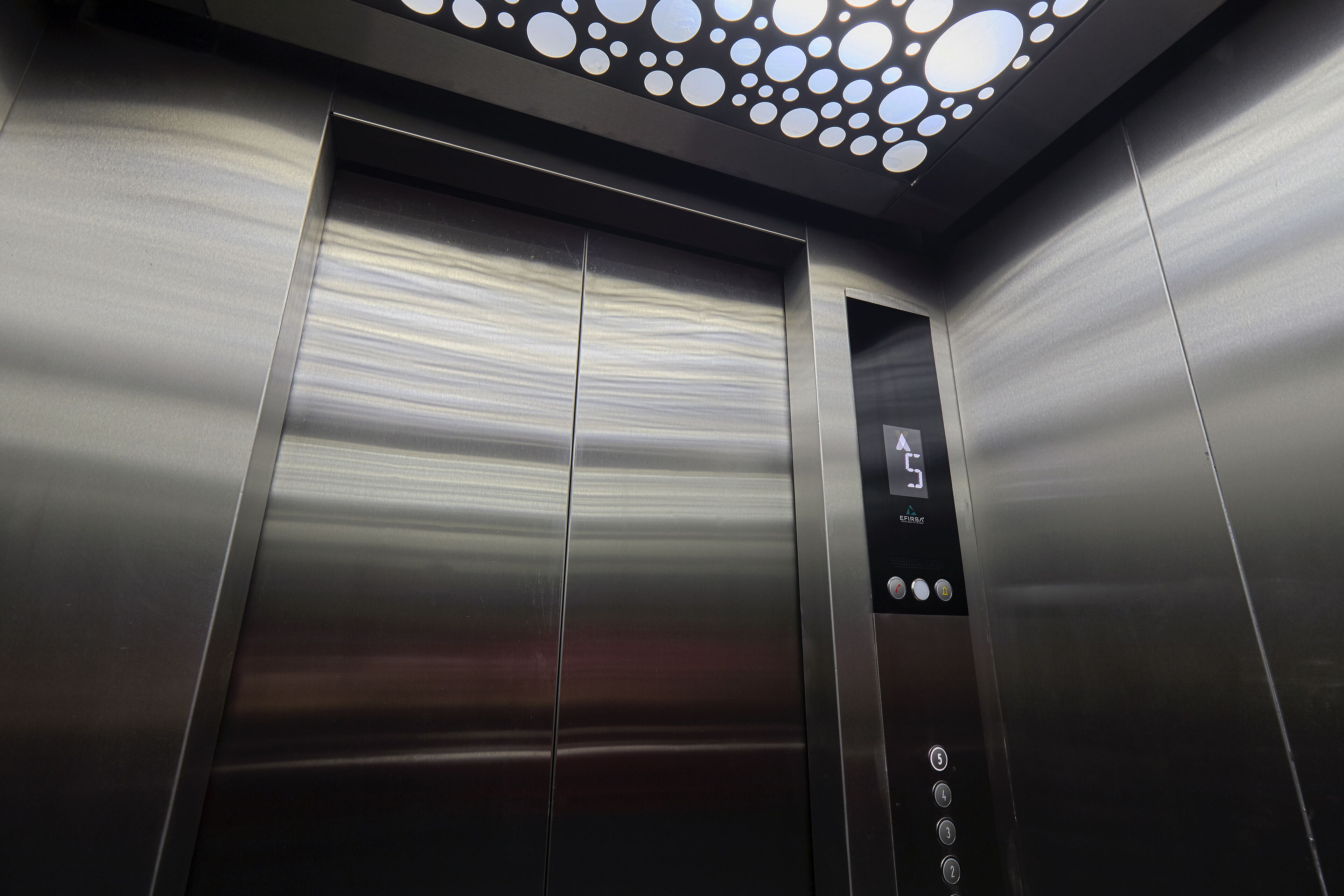 An elevator interior with metallic walls and a digital display.
