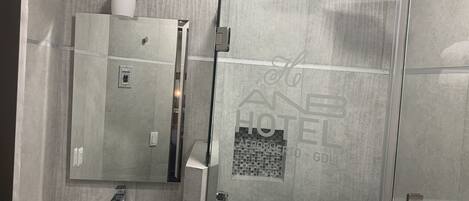 A modern bathroom with a glass shower enclosure, a white sink, and a mirrored cabinet.