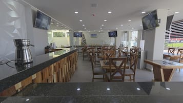 A modern restaurant with a long counter, multiple TVs, and a Christmas tree.