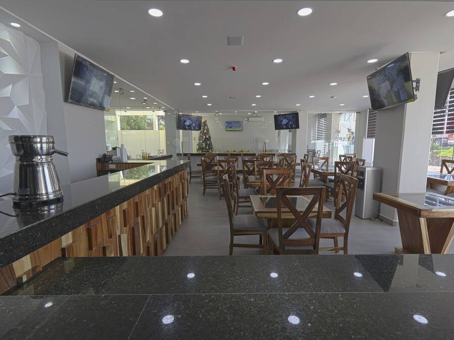 A modern restaurant with a long counter, multiple TVs, and a Christmas tree.