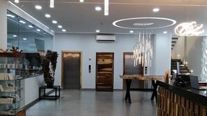 Un espace d’accueil moderne, doté d’un comptoir de réception en bois, d’une vitrine et d’une grande plante en pot.