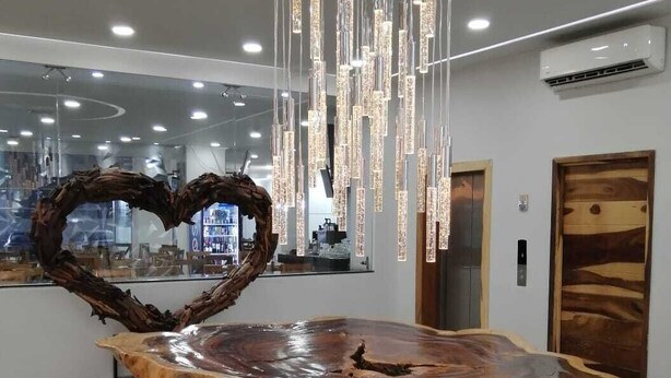 Un espace d’accueil avec une table en bois, une sculpture en forme de cœur et un lustre moderne.