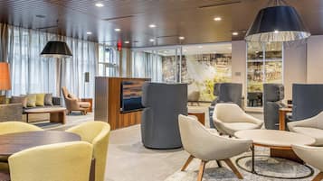 A modern lobby with seating areas, a reception desk, and a large window with a view.