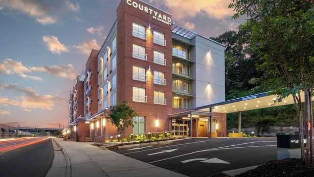 A Courtyard by Marriott hotel with a brick facade, multiple floors, and a covered entrance. - Courtyard by Marriott Asheville Biltmore Village (Asheville)