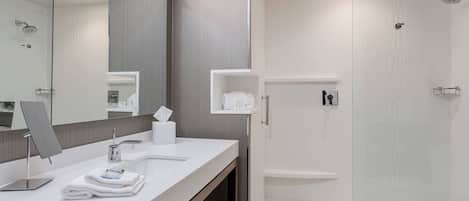 A modern bathroom with a large mirror, a sink, and a shower area.