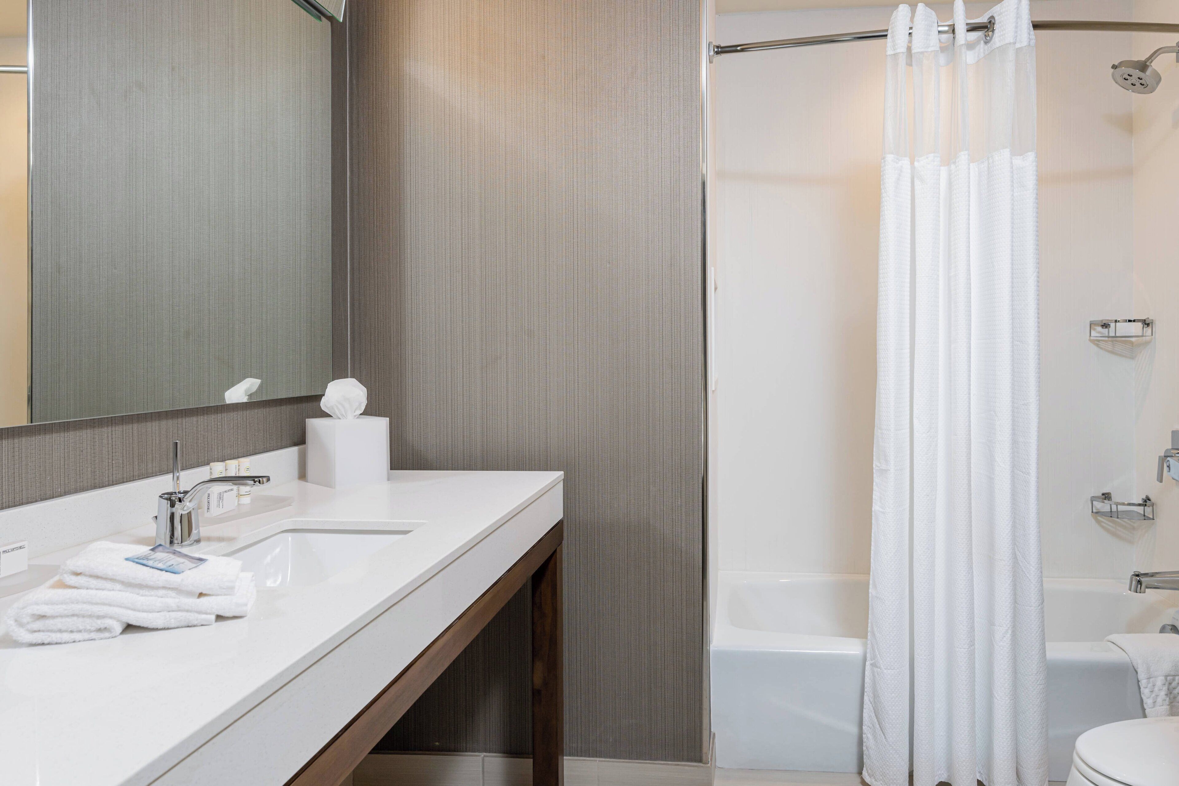 A modern bathroom with a white sink, mirror, and shower area.