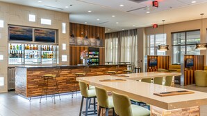 A modern bar area with a long counter, bar stools, and a variety of liquor bottles. - Courtyard by Marriott Asheville Biltmore Village (Asheville)
