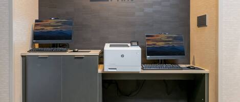 Zona de Quick Print con dos computadoras de escritorio, una impresora y un armario.