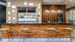 A bar area with a wooden counter, bar stools, a beverage display, and a menu board. - Courtyard by Marriott Asheville Biltmore Village (Asheville)