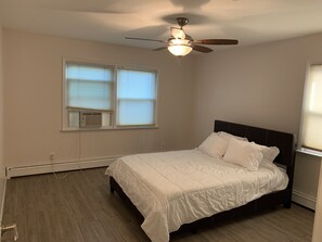 A bedroom with a bed, a ceiling fan, and a window with blinds.