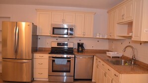 Una cocina moderna con electrodomésticos de acero inoxidable, microondas, horno y lavavajillas, además de armarios de colores claros.