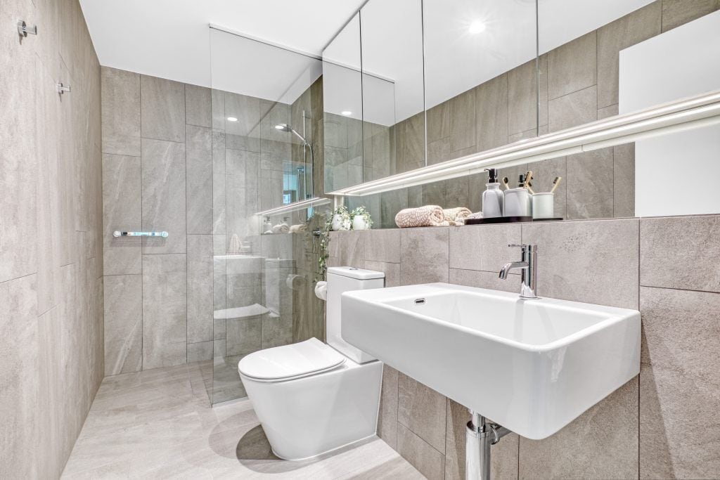 A modern bathroom with a glass shower enclosure, a white sink, and a toilet.