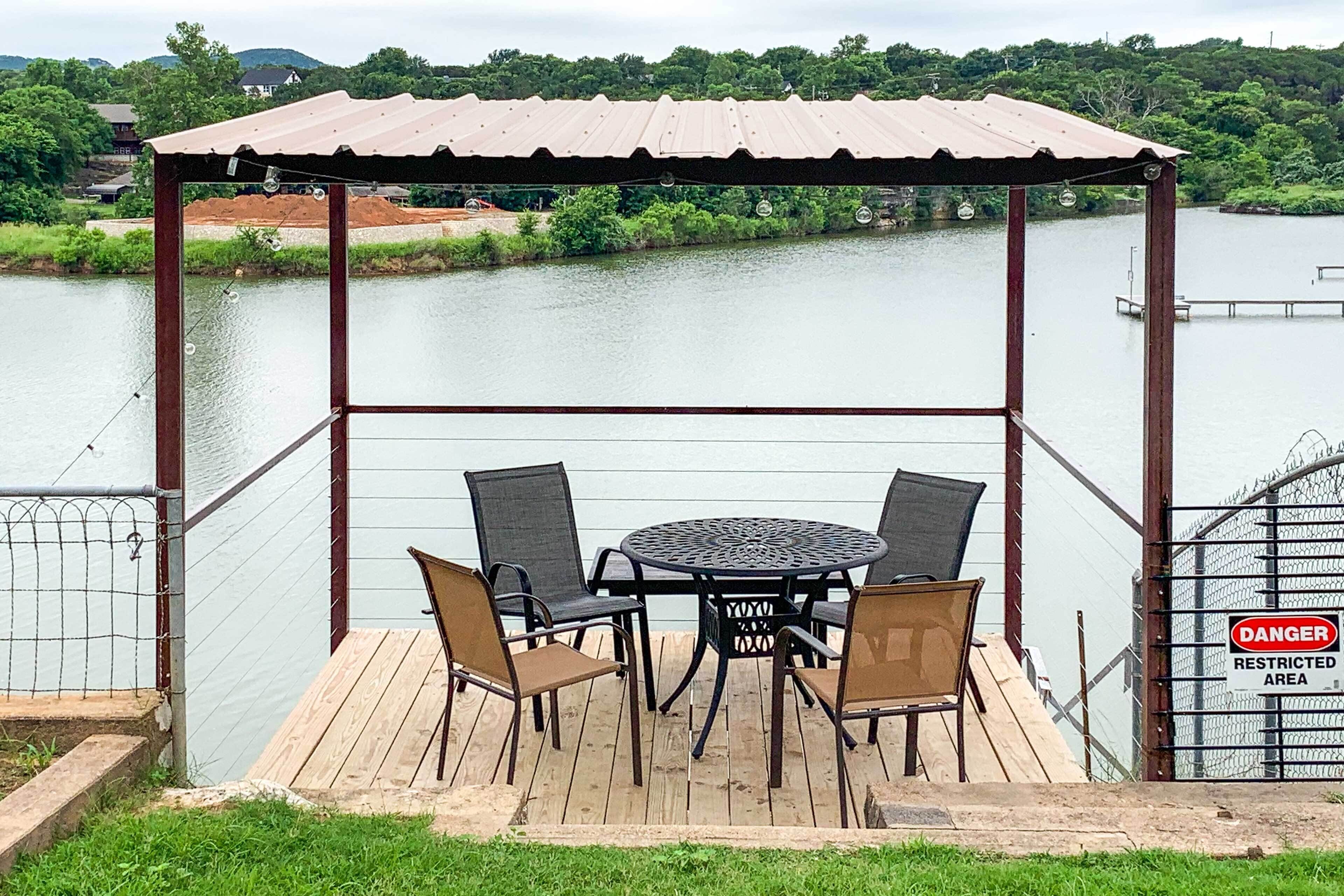 Un espace extérieur abrité, avec une table et des chaises, donnant sur une étendue d’eau.