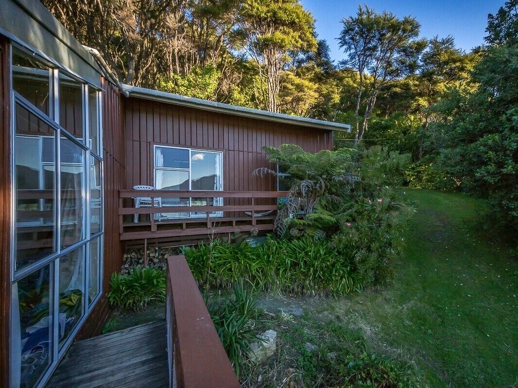 A wooden cabin with a deck, surrounded by lush greenery and trees.