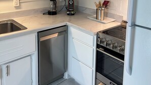 A modern kitchen with white cabinets, a stainless steel dishwasher, a built-in microwave, a gas stove, and a refrigerator. -   Healthy, relaxing , romantic , organic vacation                   - (Naples)