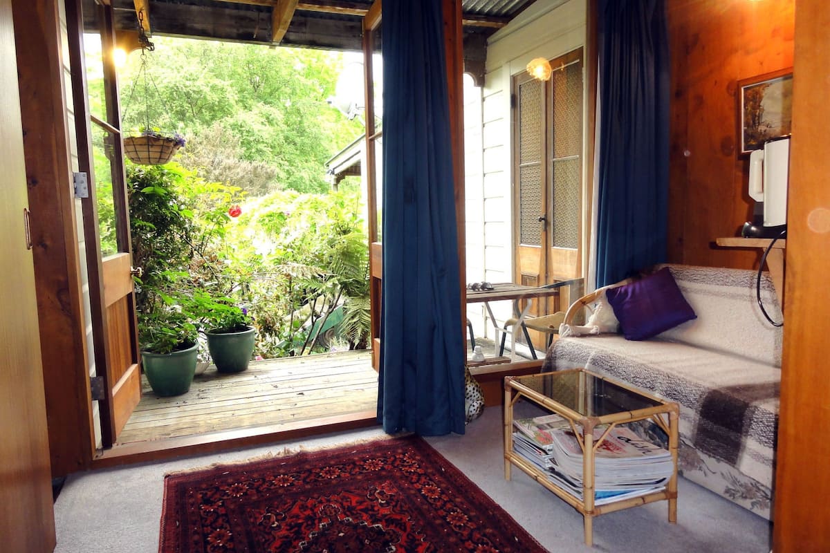 Une pièce confortable avec un canapé, une petite table et une grande fenêtre avec des rideaux.