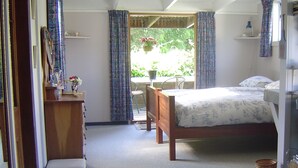 A bedroom with a bed, a dresser, a chair, and a window with curtains. - Mairenui Rural Retreat (Rangiwahia)