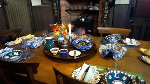 A dining table set with various dishes, bowls, and a teapot, surrounded by chairs. - Mairenui Rural Retreat (Rangiwahia)