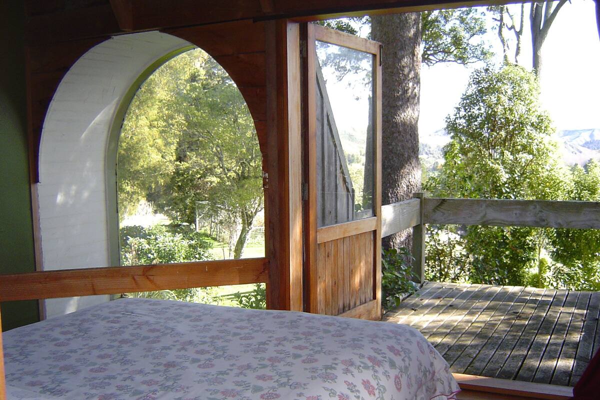 Une terrasse en bois avec un lit agrémenté d’une couvre-lit à motifs floraux.