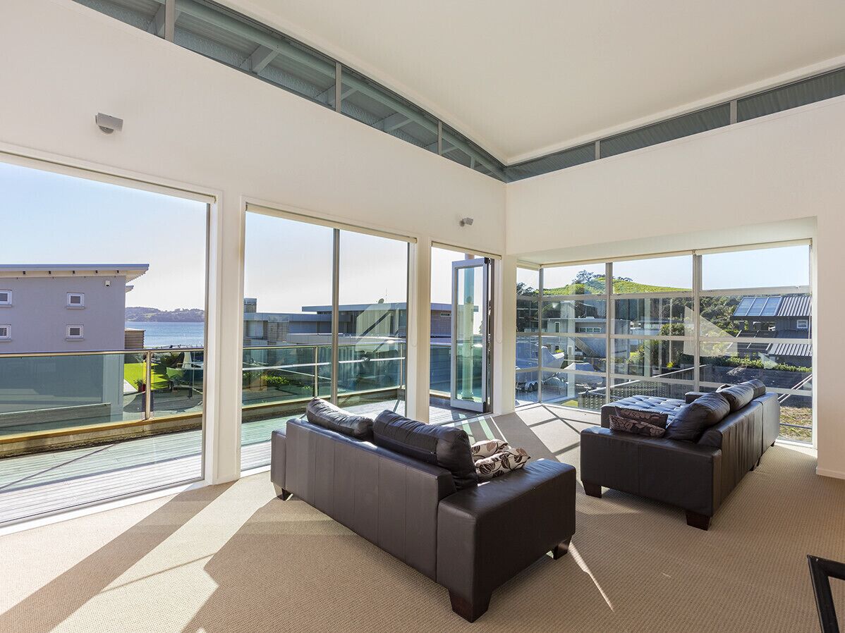 Un salon spacieux doté de grandes fenêtres, de deux canapés et d’une balustrade en verre offrant une vue panoramique.