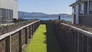 A pathway leading to a body of water with a view of hills in the distance. - Ocean Escape - Omaha Holiday Home (Omaha)