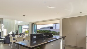 A modern kitchen with a large island, built-in appliances, and a dining area with a sofa and chairs. - Ocean Escape - Omaha Holiday Home (Omaha)