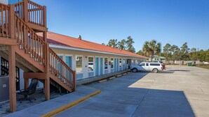 A motel with a row of rooms, a staircase, and a parking area.