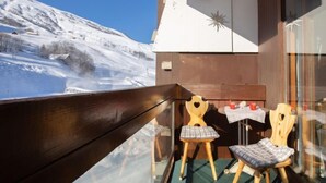 A balcony with a view of a snowy mountain. There are two wooden chairs and a small table with a red cup. - Vostok Zodiaque by Interhome (Le Corbier)