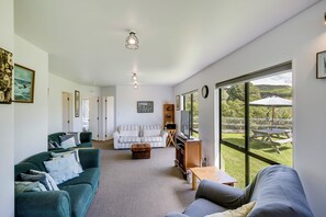 A spacious living room with a large window, a sofa, a coffee table, and a television.