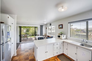 A modern kitchen with white cabinets, a built-in microwave, and a large window.