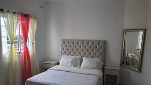 Une chambre bien rangée, avec un grand lit, deux tables de chevet et un miroir au mur.