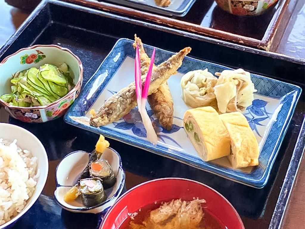 A tray with various Japanese dishes including sushi, tempura, and rice.