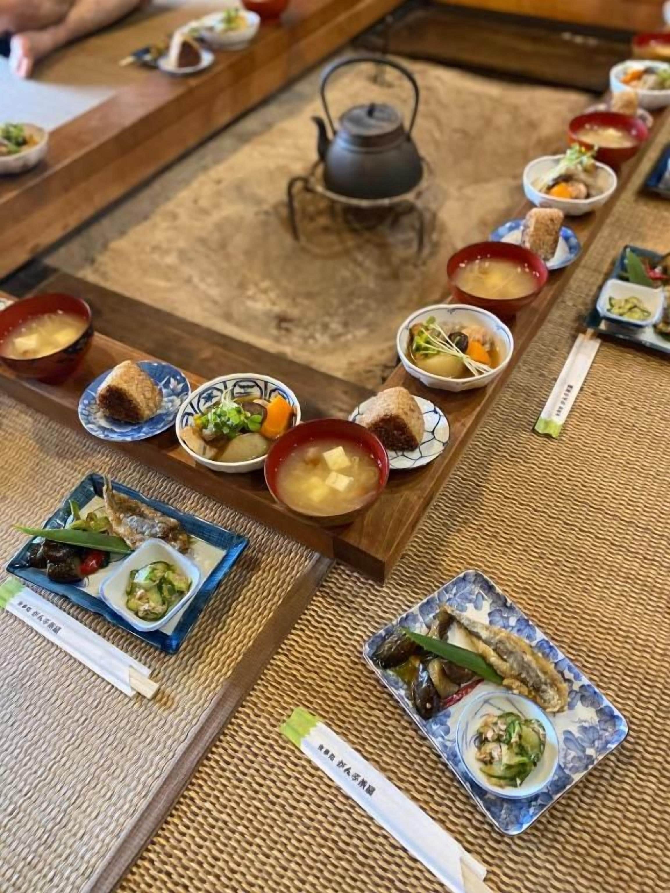 Une cérémonie du thé japonaise traditionnelle, avec plusieurs bols de thé et de petites assiettes de nourriture disposées sur un tatami.
