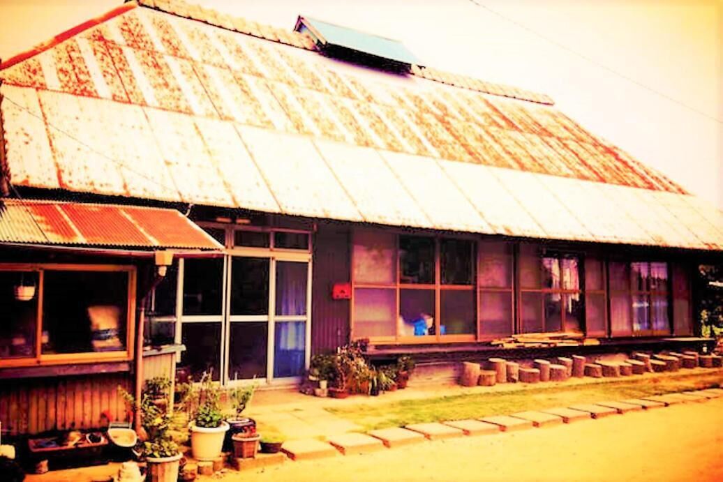 A rustic building with a corrugated metal roof and large windows.