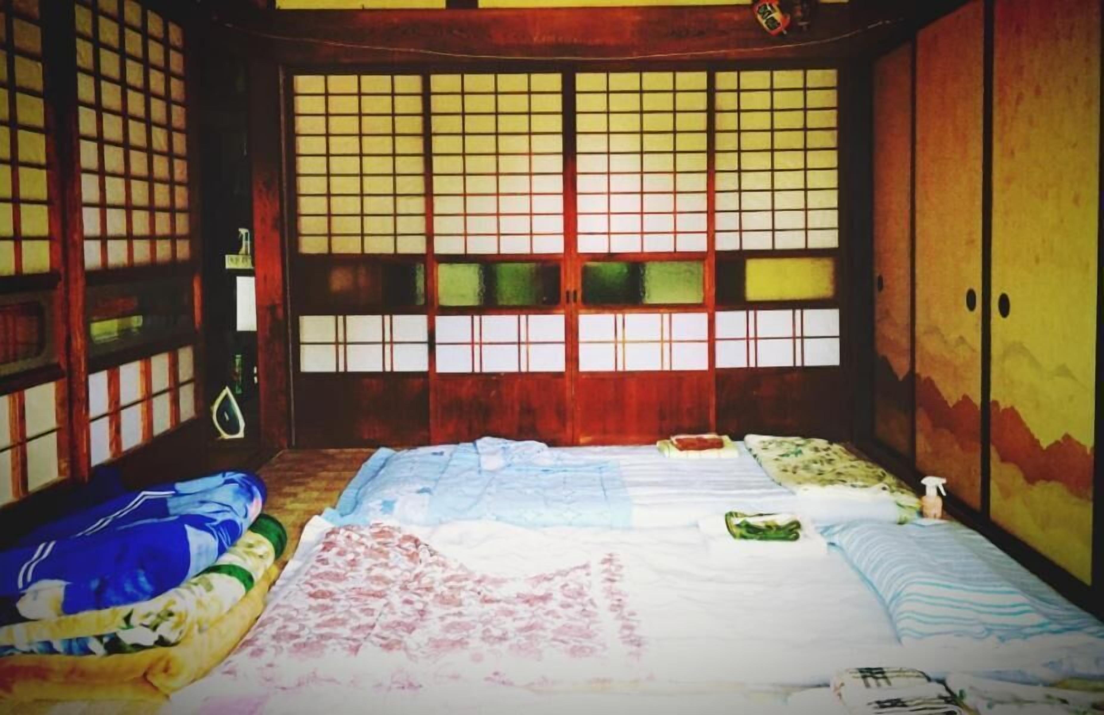 A traditional Japanese room with tatami flooring, a low wooden bed, and shoji screens.