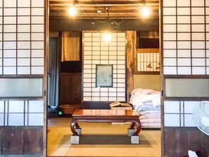 A traditional Japanese room with tatami flooring, a low wooden table, and shoji screens. - GAMP HOUSE 300 Year Old Farmhouse Hostel (Iwaki)