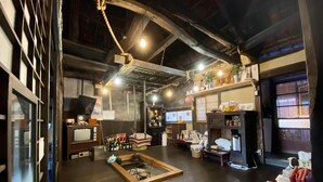 Una habitación amplia con suelo de madera, una chimenea central y varios objetos sobre estantes y mesas.