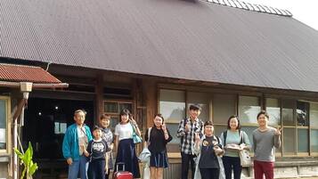 A group of people standing in front of a building with a large window and a metal roof.
