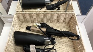 A wicker basket containing curling irons and a hairdryer on a white cabinet. - Oval Tokyo Ikesan 101 (Tokyo)