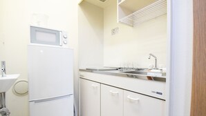 A compact kitchen with a white refrigerator, a sink, and a microwave. - Oval Tokyo Ikesan 101 (Tokyo)