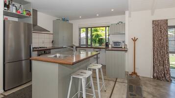 A modern kitchen with a central island, stainless steel appliances, and a large window providing natural light.