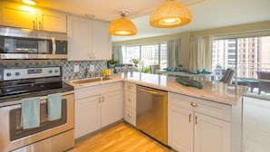 A modern kitchen with stainless steel appliances, a dishwasher, and a large window providing natural light. - Ilikai Luxury Suites (Honolulu)