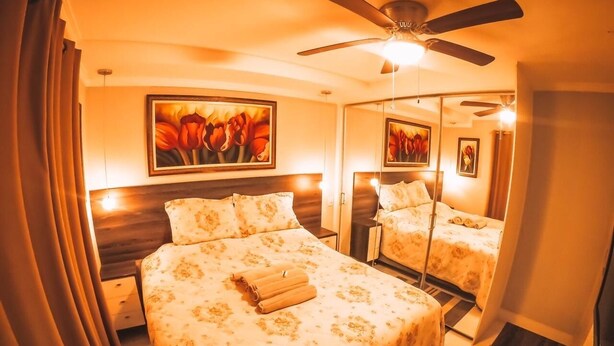 Ein Hotelzimmer mit einem großen Bett, einem Deckenventilator und zwei Wandspiegeln.