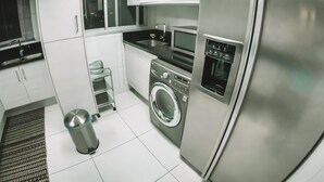 Eine moderne Küche mit Edelstahlgeräten, einer Waschmaschine und weißen Schränken.